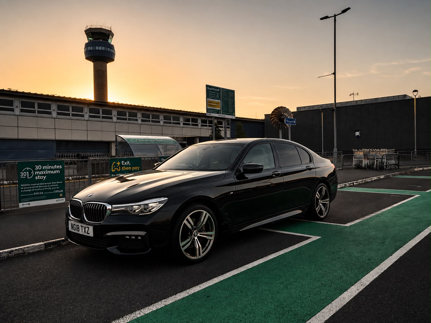Black BMW outside the airport terminal at sunset